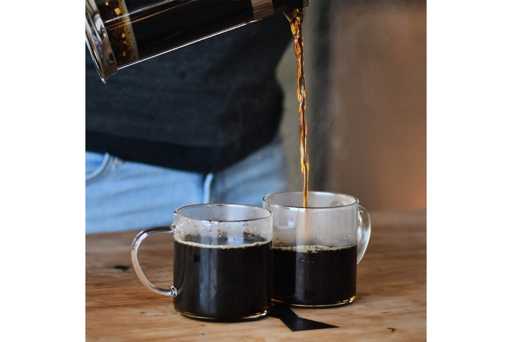 Pouring Chaga Chai Herbal Tea into two clear glass mugs